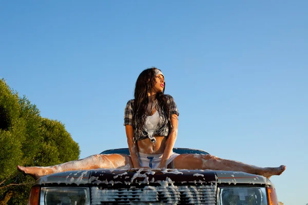 Сексуальная женщина моет машину на закате — стоковое фото