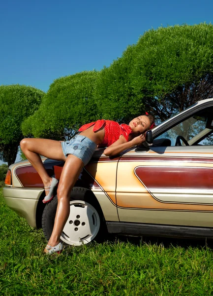 Pretty woman pin-up style lay on retro car — Stock Photo, Image