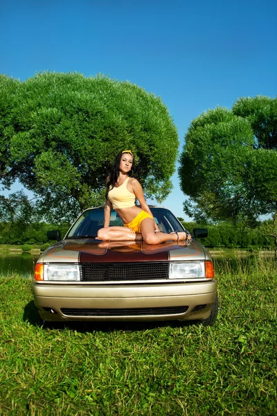 Sexy junge Frau sitzt auf Retro-Auto — Stockfoto