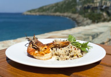 The dish with srimps and rice near mediterranean shore. clipart