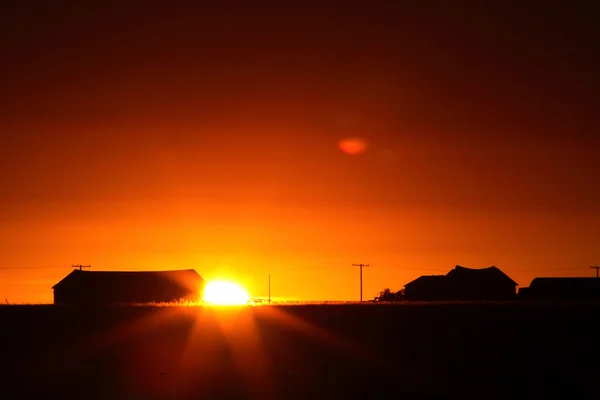 サスカチュワン州の農場の建物の背後に昇る太陽 — ストック写真
