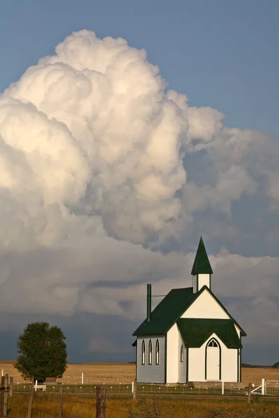 Nuvens que se formam atrás de uma igreja rural — Fotografia de Stock