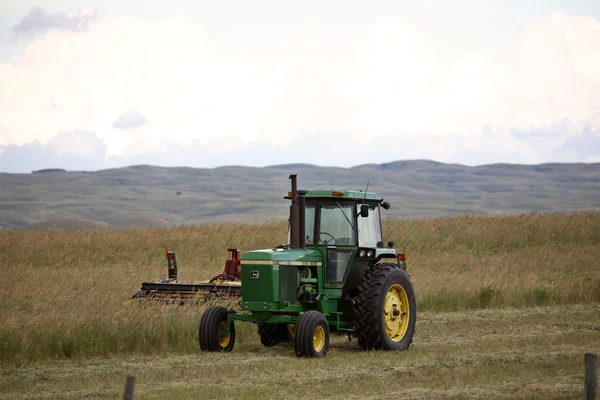 Tractor y swather a la izquierda en un campo en Saskatchewan escénico — Foto de Stock