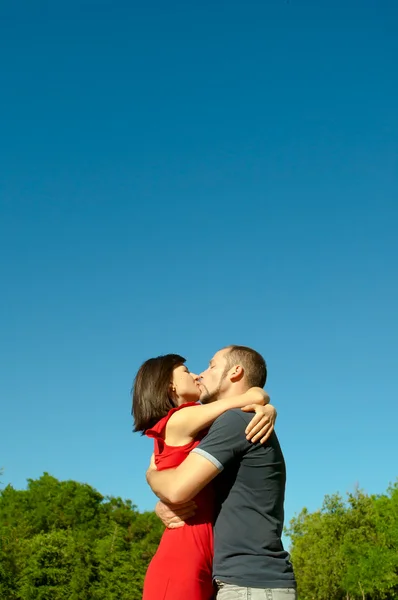 O casal amoroso beija sob o céu azul escuro — Fotografia de Stock