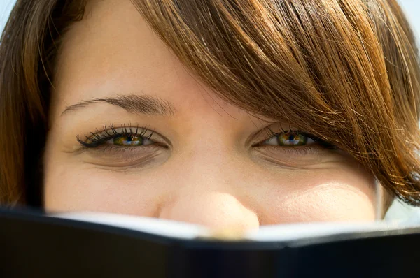 Das Mädchen schaut wegen des Buches aus nächster Nähe — Stockfoto