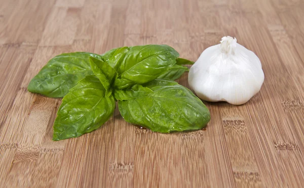 Fresh basil and garlic on bamboo board — Stock Photo, Image