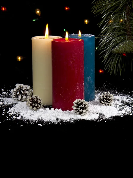 Pokryte śniegiem świece w nocy z szyszek pionowe — Zdjęcie stockowe