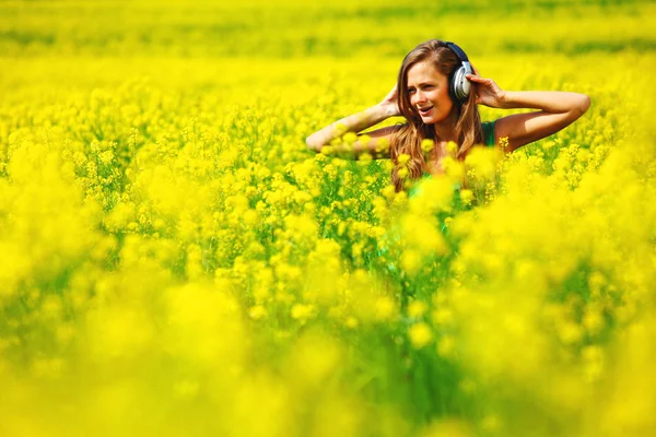 Kvinna i hörlurar på oljeväxter fältet — Stockfoto
