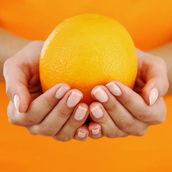 Orange i kvinna händer — Stockfoto