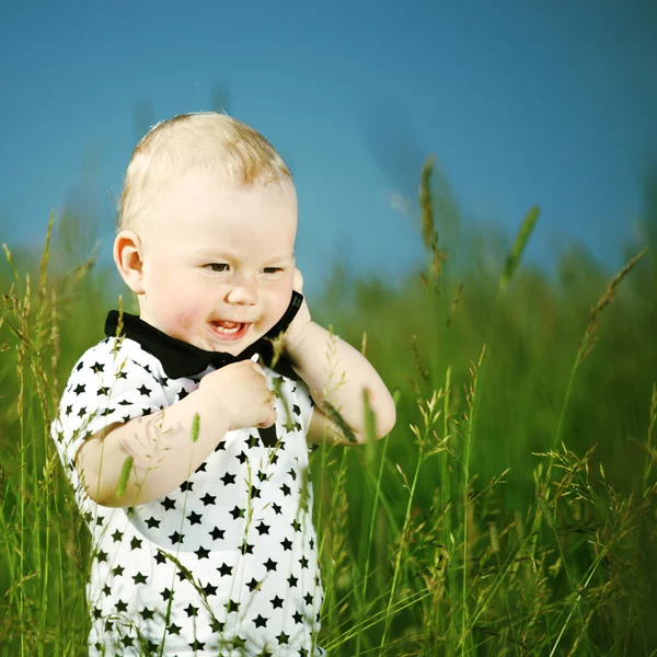 Хлопчик в траві дзвонить по телефону — стокове фото