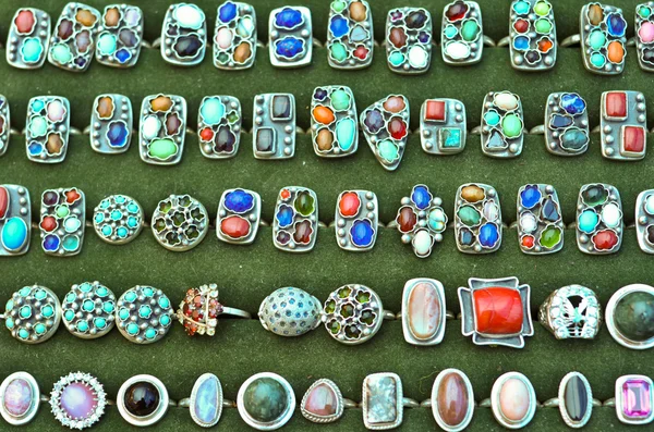 Yeşil çuha üzerindeki renkli taşlar ile antika metal halkalar — Stok fotoğraf