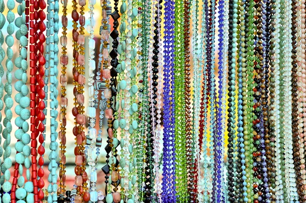 Lots of colorful glass and stone beads hanging in a row — Stock Photo, Image