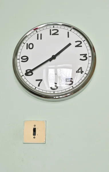 Starý elektrický spínač a moderní hodiny na zdi — Stock fotografie