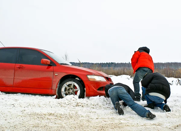 Üç kazıp kar kırmızı arabada sıkışmış — Stok fotoğraf