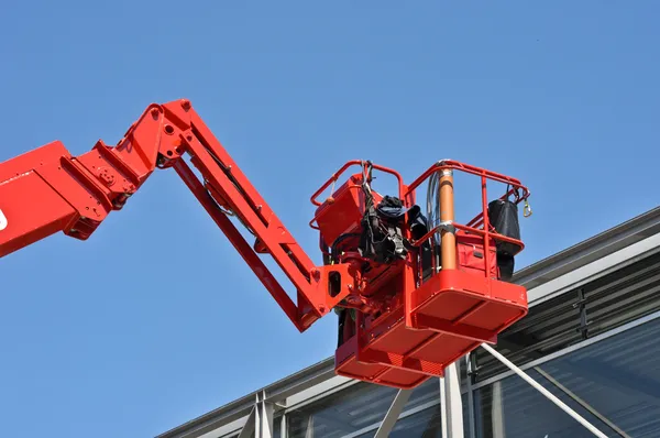 Красная гидравлическая строительная колыбель против голубого неба — стоковое фото