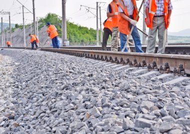 Railway embankment, rails and workers in orange vests clipart