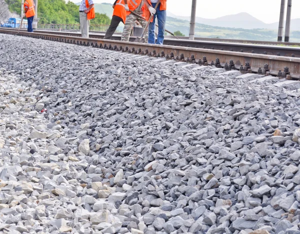 Vasúti töltés, sínek és narancssárga mellényes munkások — Stock Fotó