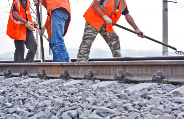 stock image Railway embankment, rails and workers in orange vests