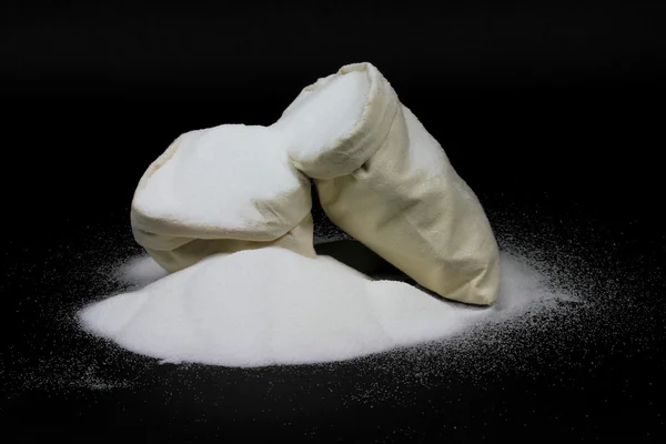 Derrame Natural de açúcar granulado de sacos em preto — Fotografia de Stock