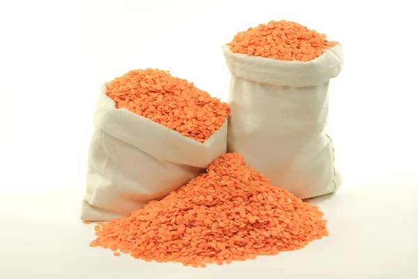 Red lentils in bags and on pile. — Stock Photo, Image