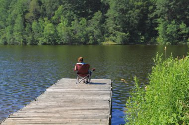 Elderly woman fishing from the dock. clipart