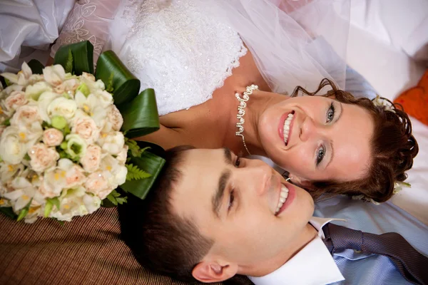 Nygift par ligger ihop på sängen Stockfoto