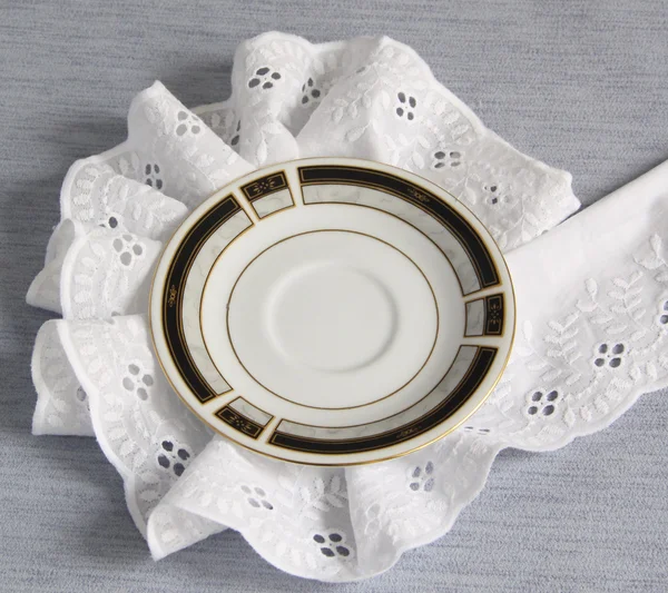 Un plato redondo en blanco a una servilleta de encaje sobre un fondo gris —  Fotos de Stock