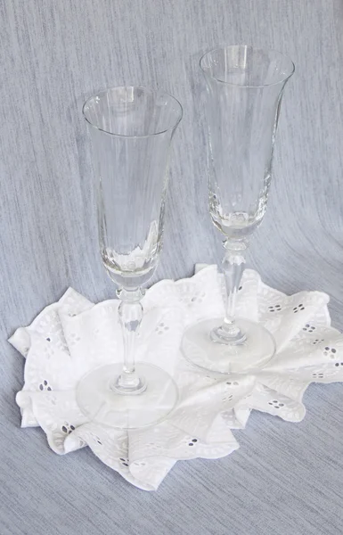 Dois copos de vidro em um guardanapo rendado em um fundo cinza — Fotografia de Stock