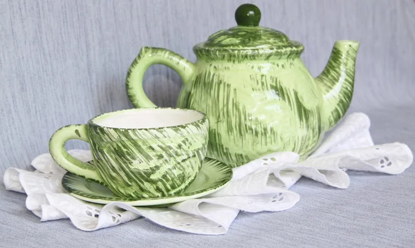 Una tetera verde y una taza en una servilleta de encaje blanco — Foto de Stock