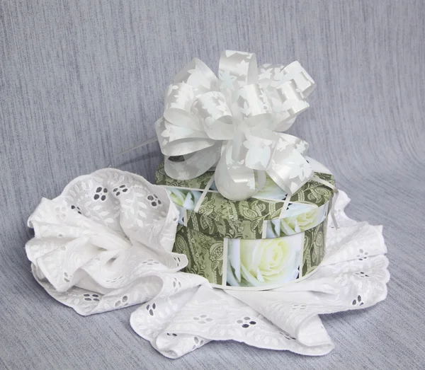A gift in a round box with a bow and a flower from laces on a grey backgrou — Stock Photo, Image