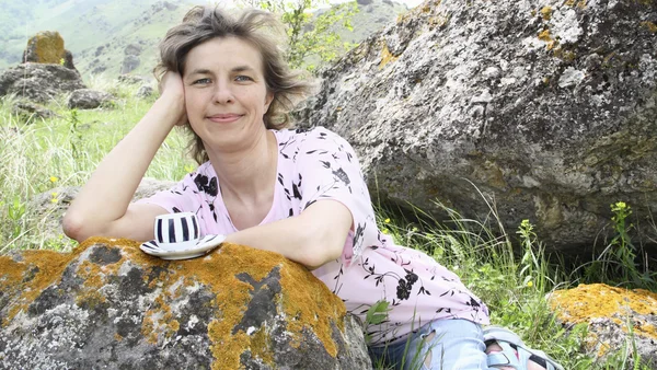 Счастливая женщина против камней с полосатой кружкой — стоковое фото