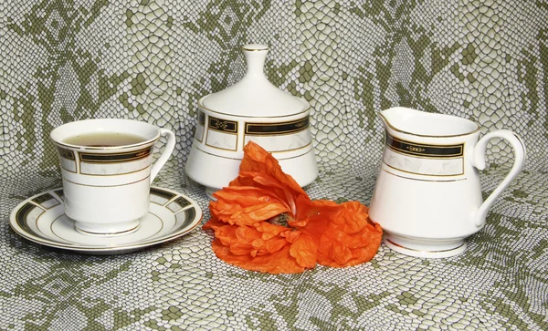 Μια κούπα τσάι, και ένα Κύπελλο ζάχαρης με ένα κόκκινο λουλούδι — Φωτογραφία Αρχείου