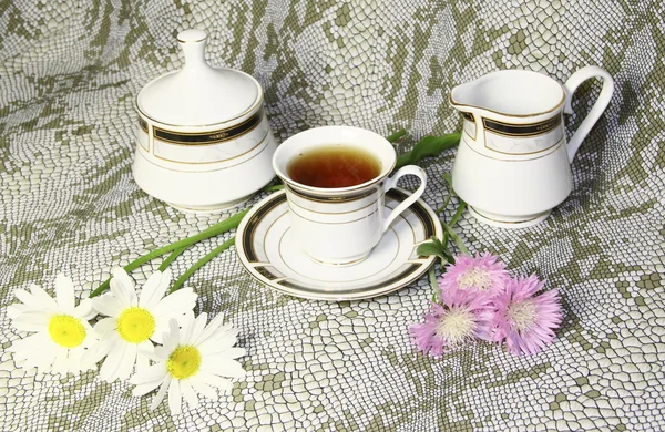 Kubek herbaty cukiernica z camomiles i różowe kwiaty dzikiego — Zdjęcie stockowe