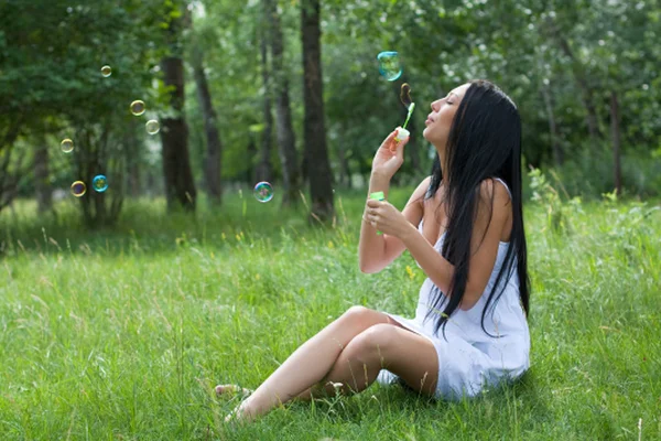 Mädchen bläst Blasen im Park auf — Stockfoto