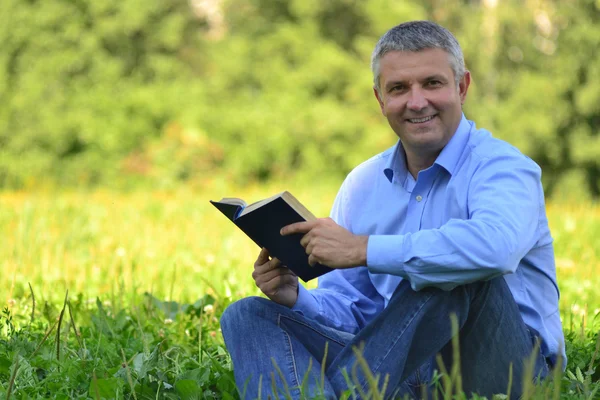 Portrait of a man in a park with a book — Stock Photo, Image