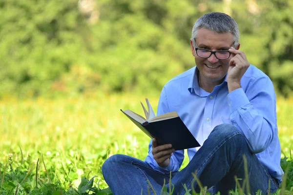 Porträt eines Mannes in einem Park mit einem Buch lizenzfreie Stockfotos