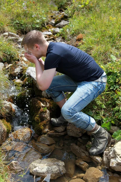 Young man taking a refreshment in the mountains — Stock Photo, Image