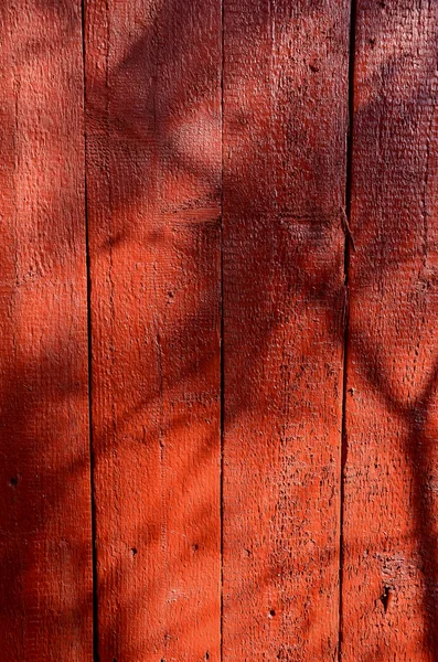 Sombras na parede de madeira pintada de vermelho . — Fotografia de Stock