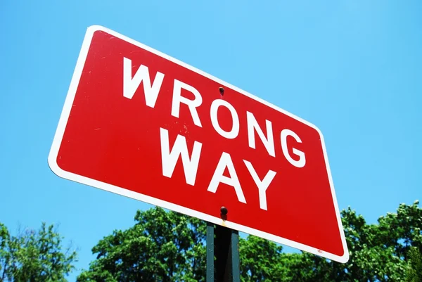 Wrong way road sign on a blue sky background — Stock Photo, Image