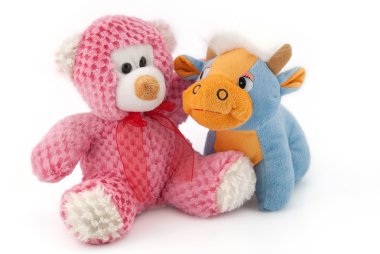 Soft toys bear and a cow on a white background have fun looking at each other clipart