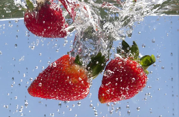 丢弃在液体中的草莓. — 图库照片