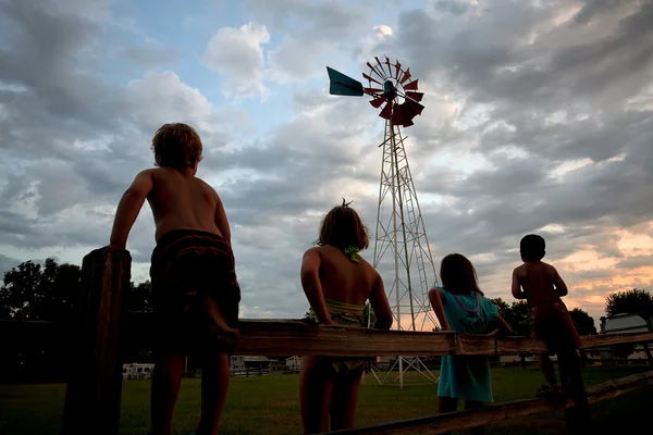 Kinderen en een windmolen bij zonsondergang. — Stockfoto