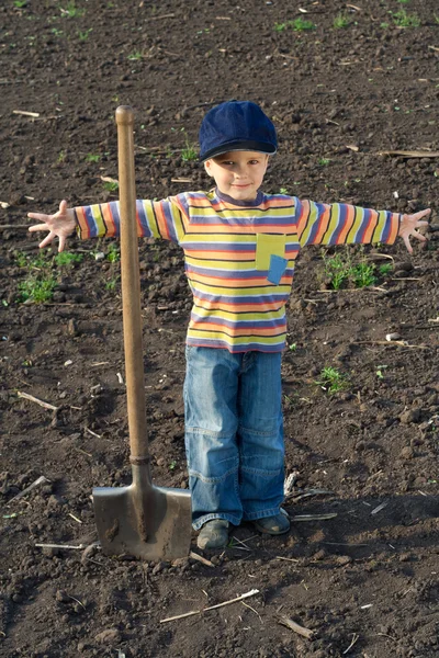 Little boy with big shovel in the field — Stock Photo, Image