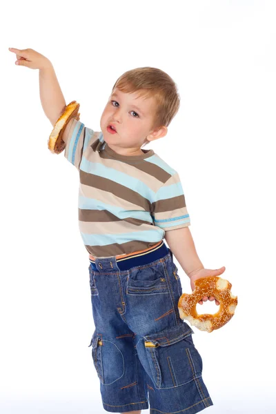 Niño pequeño con dos rosquillas y la mano apuntando —  Fotos de Stock