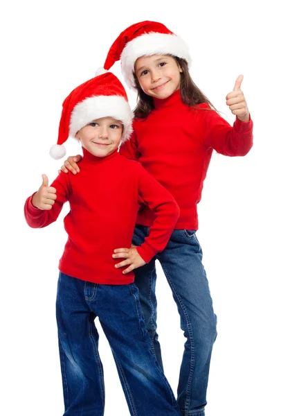 Двое детей с большими пальцами и шляпы Санты — стоковое фото