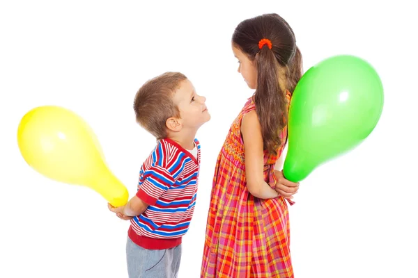 Zwei lustig lächelnde kleine Kinder mit bunten Luftballons — Stockfoto