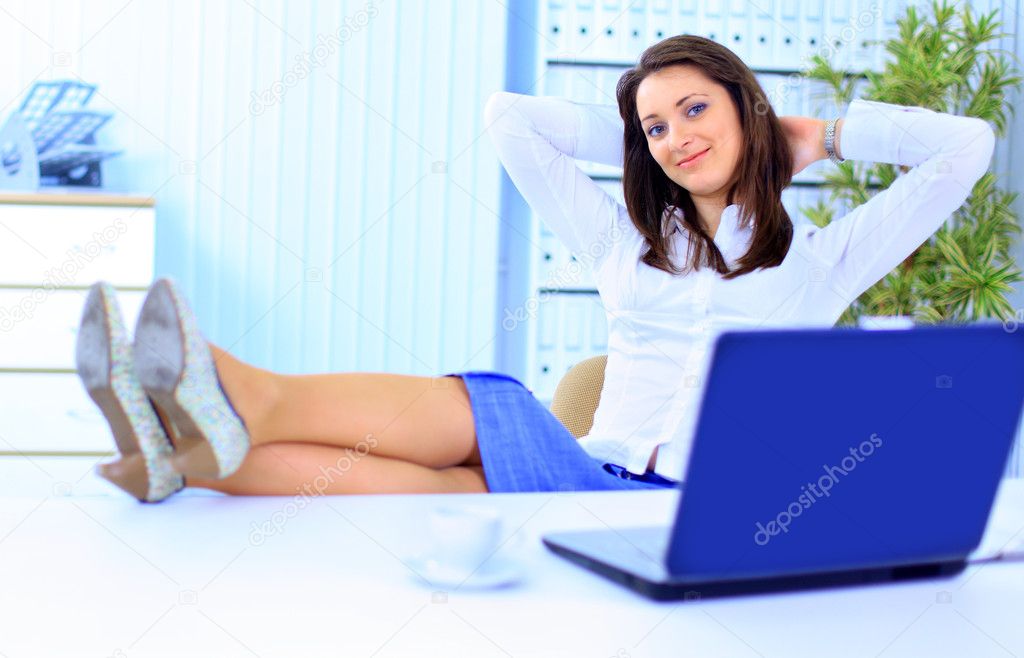 Young female executive relaxing in an office chair with hands behind ...