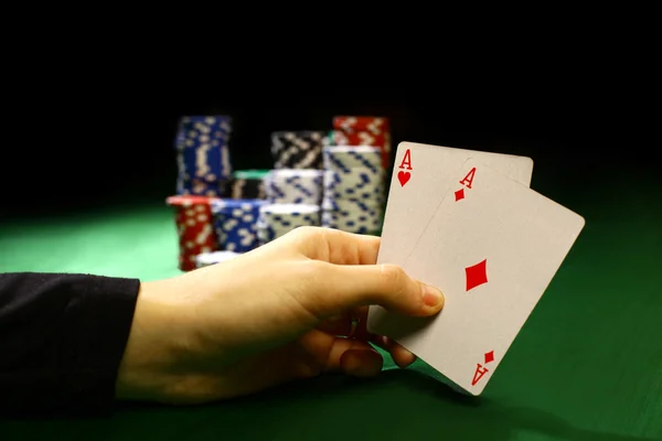 Покерні чіпи і рука перевертають карти ізольовані від зеленого фетру — стокове фото