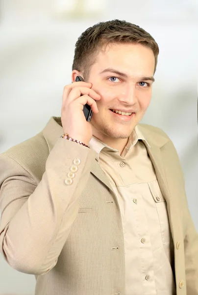 Νεαρός χαμογελαστό επιχειρηματίας καλεί το τηλέφωνο στο γραφείο — Φωτογραφία Αρχείου