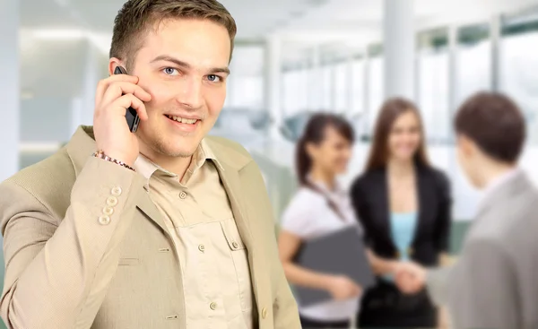 Jovem homem de negócios sorrindo chamando pelo telefone no escritório — Fotografia de Stock